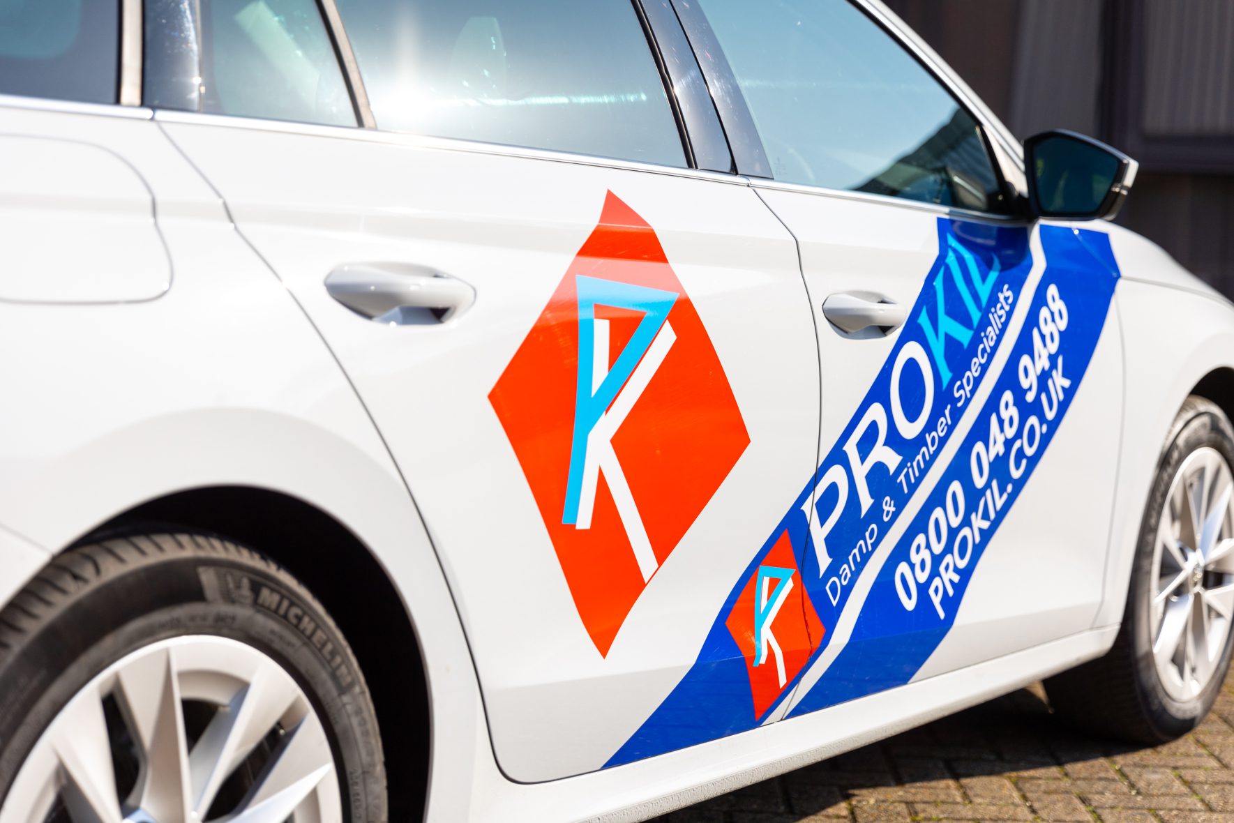 Side view of the prokil branded white car with tag line: damp & timber specialists