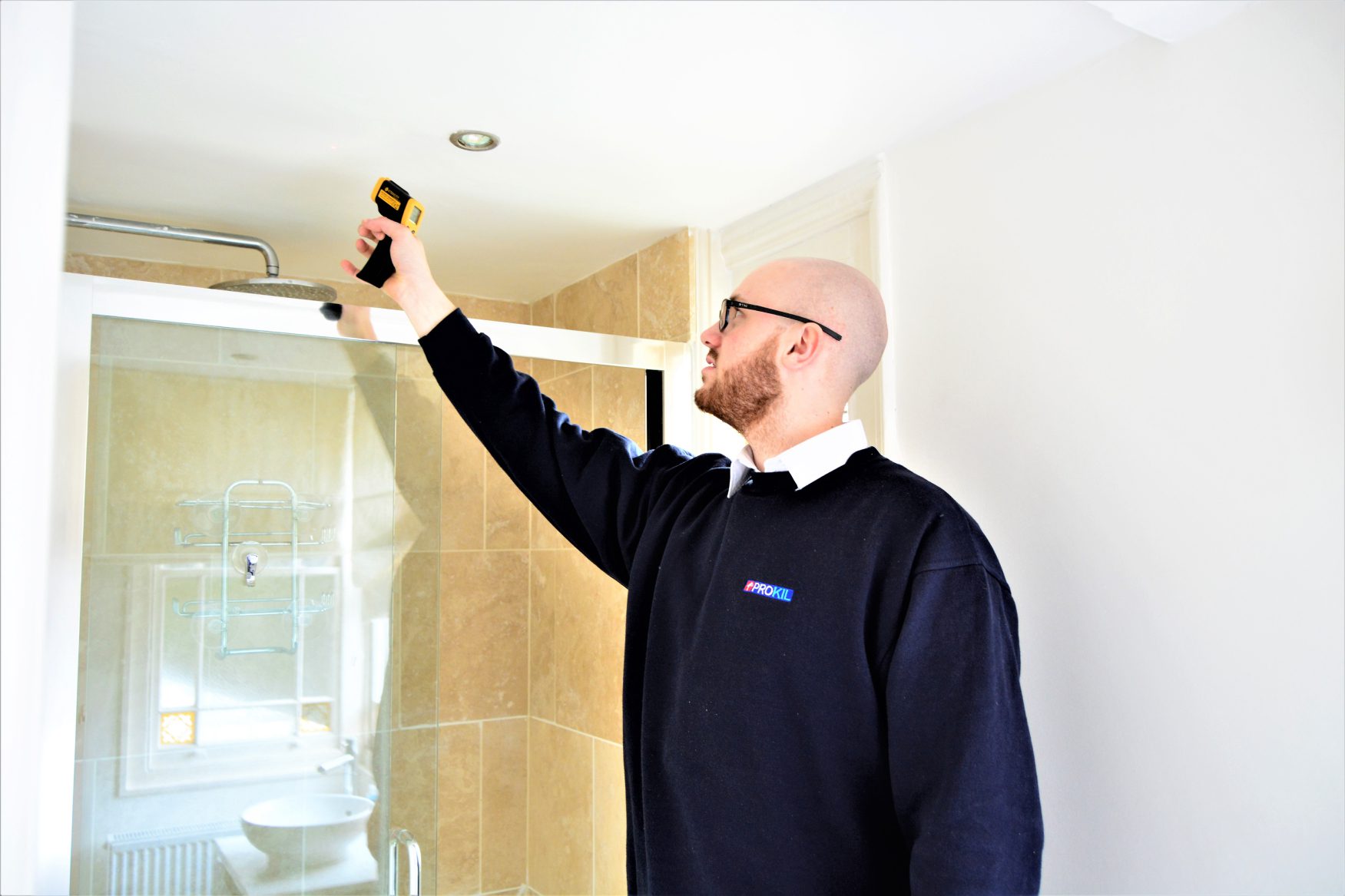 damp & timber specialist checking for moisture in a residential bathroom shower area